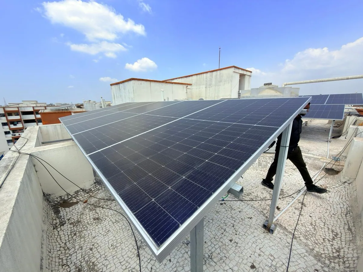 Solar panel array being assembled on a rooftop with a field technician working beside the structure