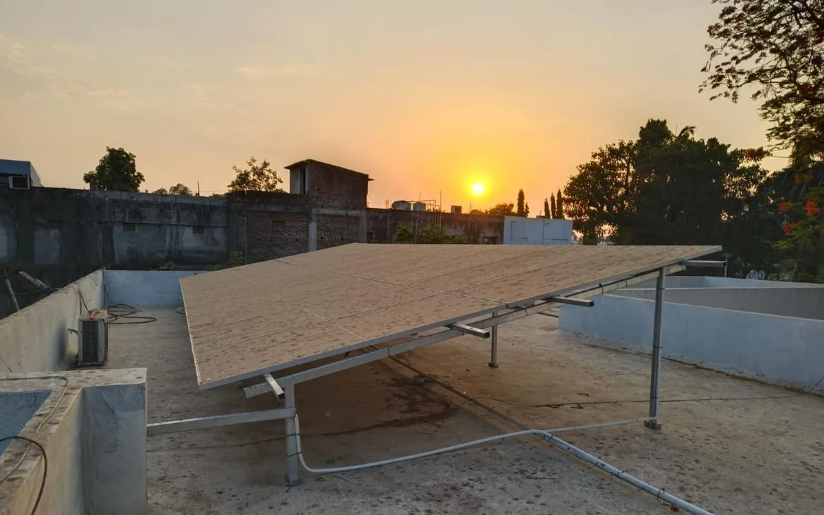 Rear view of a rooftop solar array aligned against the setting sun with a conduit route below