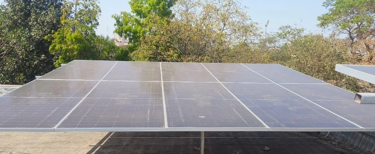 Completed low-rise rooftop solar array in Khali with trees visible beyond the roof