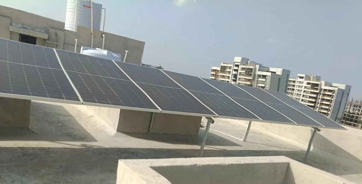 Completed rooftop solar array in Vadodara with apartment buildings beyond the roof
