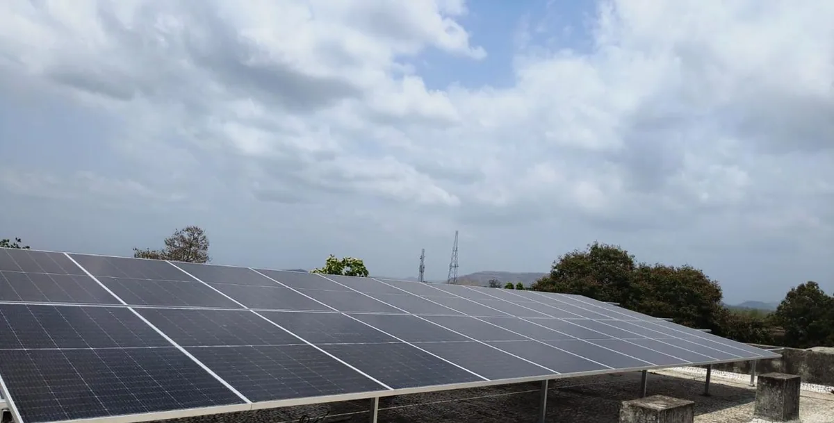 Wide view of a completed rooftop solar array in Vansda under a cloudy sky